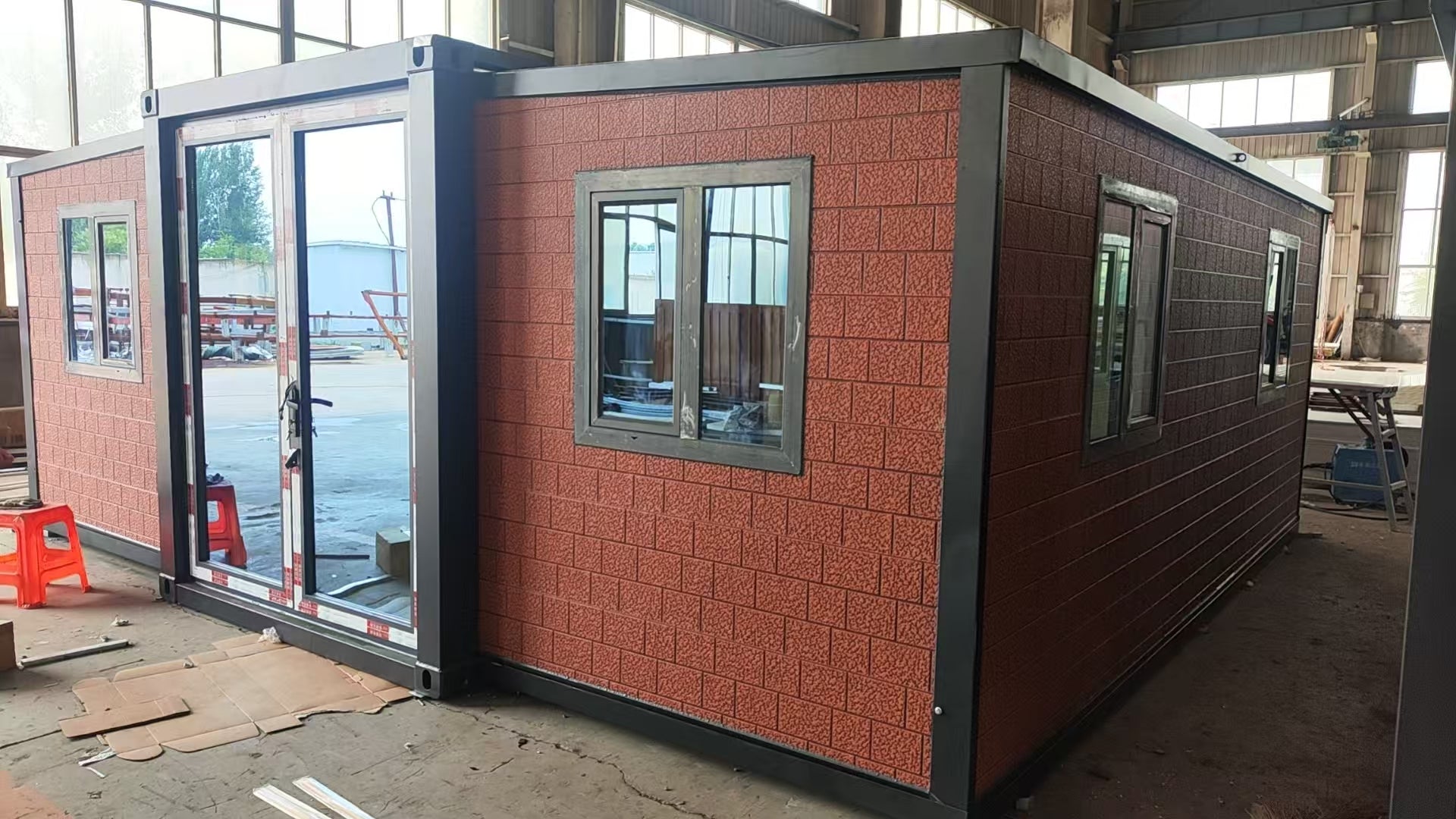 Modular building with red brick-like exterior and glass windows in an industrial setting.