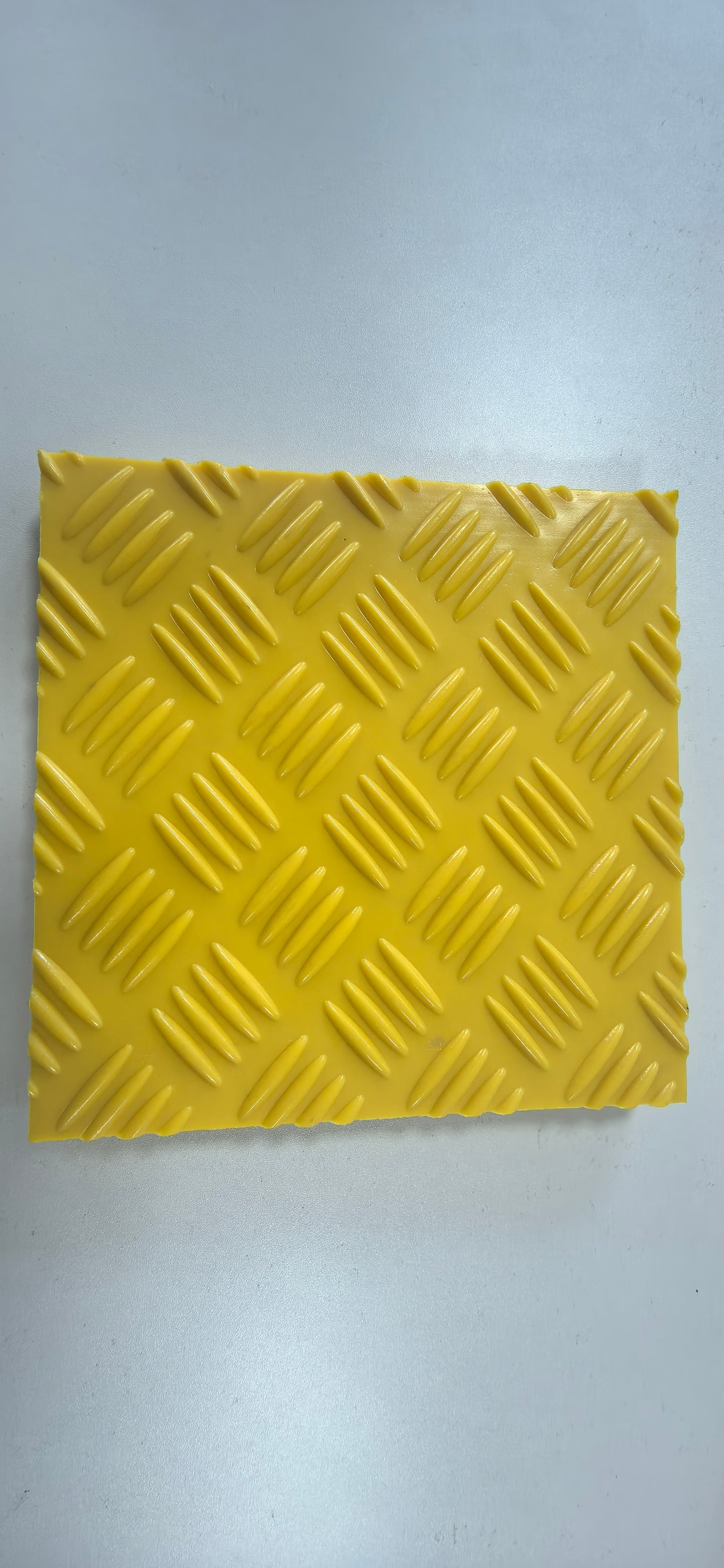 Yellow diamond plate patterned mat on a gray background