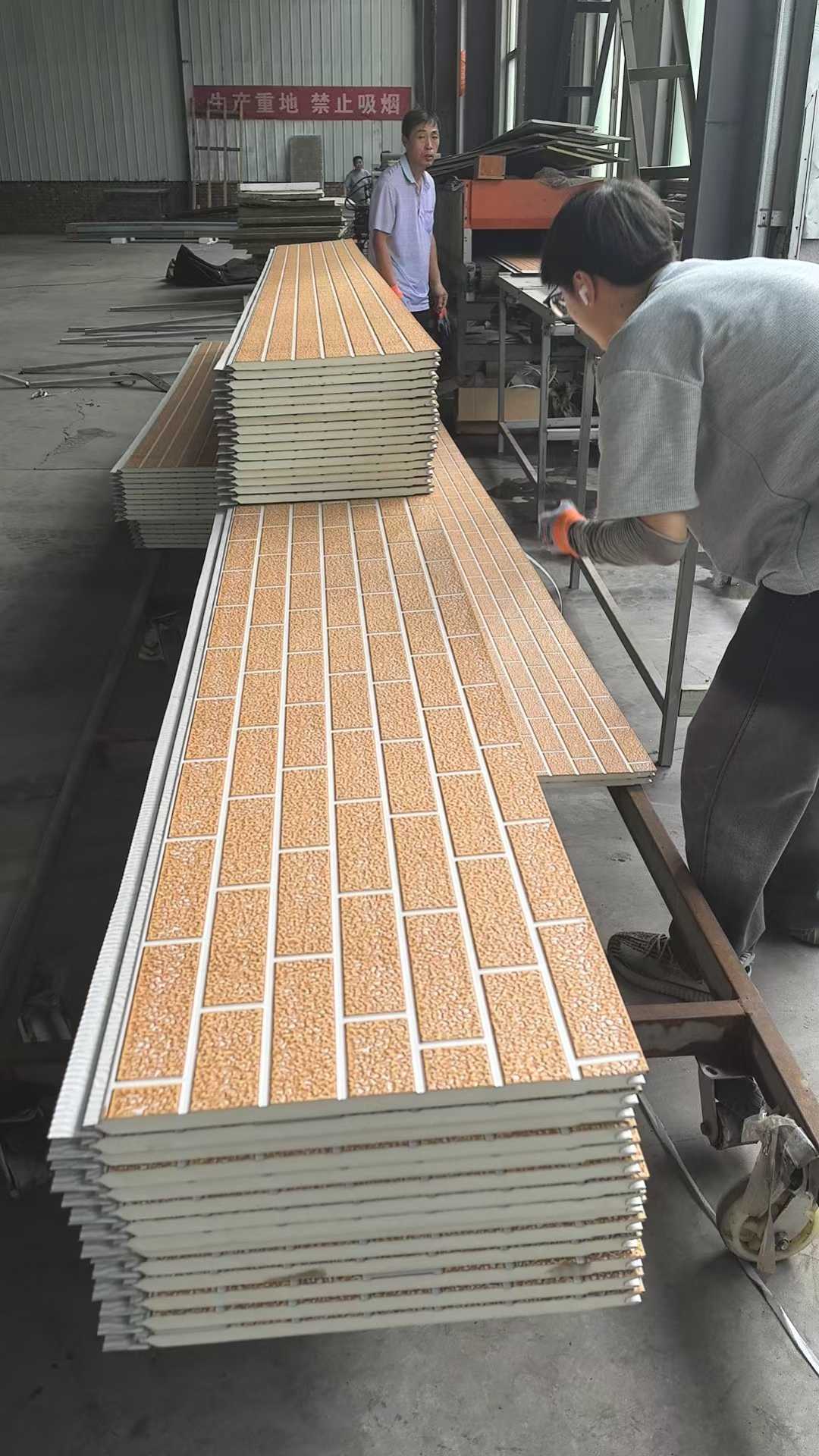 Stacks of ceramic tiles on a workbench with a person in the background.